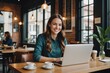 © ThomasLENNE - Smiling young female entrepreneur getting work done while sitting at a table in a cafe using a laptop