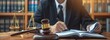A man practicing law uses a wooden gavel to work on the contract paperwork of a significant lawsuit involving a commercial client.