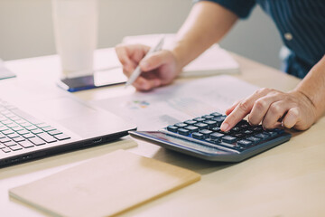 Businessman hands with calculator at the office and financial data analyzing business result and tax management. Finance accounting and economy concept.