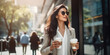 Stylish business lady with two disposable cups of coffee walks down the street on a summer morning.