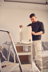 Wall Mural - Man working and assembling furniture in a new apartment.