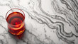 A glass of red liquid sits on a marble countertop. The countertop is covered in a pattern of black and white lines. Concept of elegance and sophistication, with the contrast between the clear glass