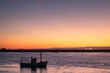 © mestock - Sunset prices on a Spanish beach with beautiful clouds, calm sea and a fishing boat in the foreground and beautiful concave crescent moon.