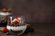 Tasty granola with berries, nuts and yogurt in glass on wooden table, space for text