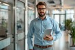 © Gromik - Man in dress shirt holding tablet in hallway with building fixture