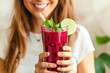Woman holding a glass of beetroot smoothie with mint and lime. Healthy lifestyle and detox diet concept for restaurant menu, food blog design.