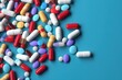numerous colorful capsules and pills on blue background