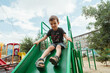 © alexkoral - preschooler boy plays on a slide on the playground in the summer