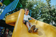 © alexkoral - happy boy rides a slide on the playground in summer