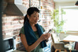© Marko Geber - Smiling Asian woman using smartphone after home workout