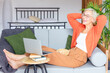 © klavdiyav - beautiful elderly senior woman in cosy apartment works on laptop, beautiful gray haired woman works online or watching movie, studies and communicates, concept of active old age