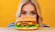 young woman peeking at cheeseburger on table