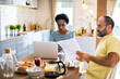 © Davor - Couple having breakfast together while woman uses laptop in the kitchen at home