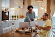 © Davor - Couple having breakfast together while woman uses laptop in the kitchen at home