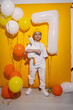 © saulich84 - photo session of a boy in a yellow hat and white T-shirt with a toy bird goose hugging standing on a yellow paper background in a studio