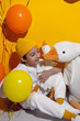 © saulich84 - photo session of a boy in a yellow hat and white T-shirt with a toy bird goose hugging standing on a yellow paper background in a studio