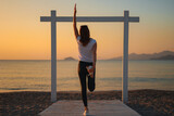 Fototapeta Tulipany - Joga, młoda dziewczyna praktykuje asany na wakacjach nad morzem. Wschód słońca na greckiej wyspie Kos. Ćwiczenia rozciągające, sport na powietrzu. 