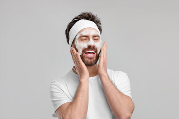 Canvas Print - Man with headband washing his face on light grey background