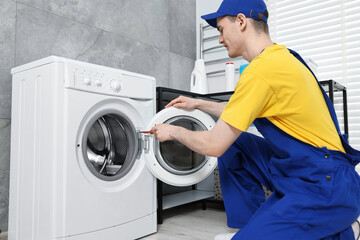 Wall Mural - Plumber repairing washing machine in bathroom, low angle view