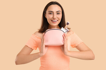 Sticker - Beautiful young woman with cosmetic bag full of makeup products on beige background