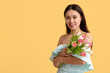 © Pixel-Shot - Happy young Asian woman with bouquet of beautiful tulips on yellow background. International Women's Day