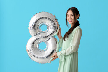 Canvas Print - Beautiful young Asian woman with silver air balloon in shape of figure 8 on blue background. International Women's Day