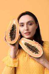 Wall Mural - Beautiful young woman with sweet papaya on yellow background