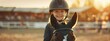 Happy girl kid at equitation lesson looking at camera while riding a horse, wearing horseriding helmet