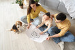© Pixel-Shot - Happy family with house plan and Beagle dog in room on moving day