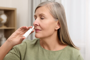 Poster - Medical drops. Woman using nasal spray indoors