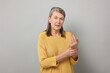 Arthritis symptoms. Woman suffering from pain in wrist on gray background