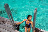 Fototapeta Londyn - Beach travel vacation luxury woman in hotel villa swimming from ocean deck wearing bikini. This image is completely unretouched and unedited and model is with no makeup. Original Raw Image.