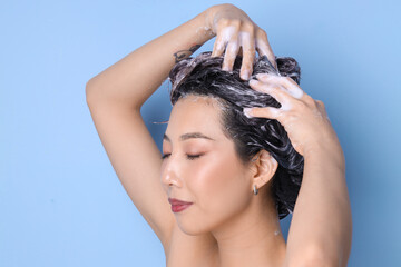 Sticker - Young Asian woman applying shampoo on blue background, closeup