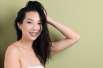 Poster - Young Asian woman with wet hair on green background, closeup