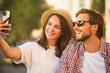 © opolja - Loving cheerful happy couple taking selfie in the city.
