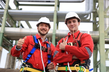 Portrait of two male engineers looking at the camera and the thumbnails of their successful project at a piping line in a petrochemical plant.