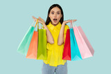 Fototapeta  - Excited surprised young woman with shopping bags at blue backgtound