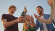 © stockbusters - Friends holding champagne bottle having fun together at outdoor party close up.