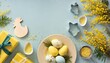 easter concept top view photo of yellow present boxes plate with easter eggs mimosa flowers chicken baking molds and sprinkles on isolated pastel blue background with empty space in the middle