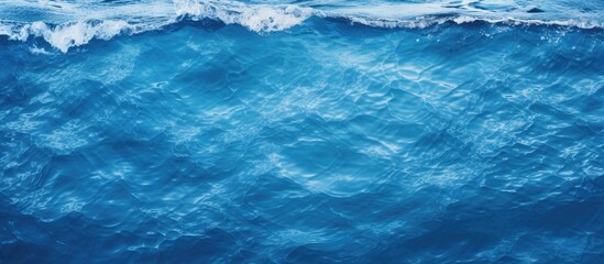 Wall Mural - A captivating closeup shot of electric blue water with wind waves crashing onto the shore, showcasing the beauty of natural water resources