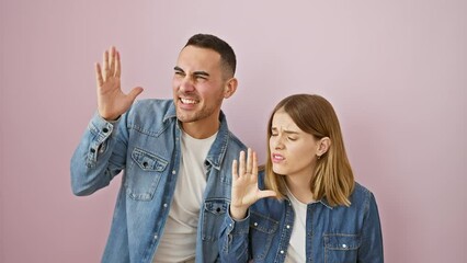 Sticker - Furious and beautiful couple in denim, yelling away - a shout aside with open mouth screams loud from man and woman standing over pink isolated background! it's crazy communication love!