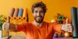 Fitness trainer in orange shirt holding yoga mat giving thumbs up in home gym on yellow background. Concept Fitness, Trainer, Home Gym, Yoga Mat, Thumbs Up