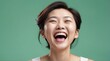 young chinese middle aged woman on plain bright green background laughing hysterically looking at camera background banner template ad marketing concept from Generative AI