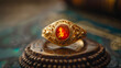 An antique gold ring adorned with a glowing red opal stone rests gracefully on a carved wooden piece, evoking a sense of timeless beauty