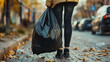 © Alina Tymofieieva - A person is holding a black trash bag on the sidewalk. The bag is full and ready to be taken to the trash can. The scene is simple and straightforward, with no additional elements or distractions