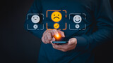 Fototapeta Kosmos - Engaging in an online customer feedback survey, a user utilizes their mobile phone to display an angry emoticon on a virtual screen, sharing their opinion and reviewing service satisfaction.