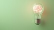 A conceptual 3D render of a light bulb with a brain inside, glowing subtly on a pastel lime green background, denoting eco-friendly innovation