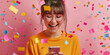 © FATHOM - Happy young woman using her smart phone with confetti