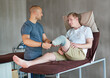 © peopleimages.com - Therapist, man with disability or prosthetic as medical, recovery or fitting in hospital for health. Bed, patient or leg in exam, help or physio as healthcare, orthopedic or rehabilitation progress