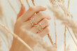 Close-up of a woman's hand with gold minimalist rings on her fingers.